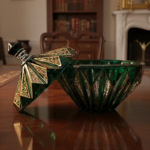 ظرف درب‌دار کریستالی یا شیشه‌ای سبز زمردی با تراش‌های هندسی لوزی و تزیینات طلایی رنگ طرح‌دار.