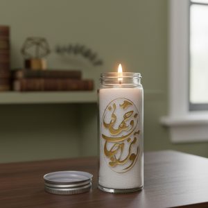 "شمع تزئینی با خطاطی فارسی طلایی در لیوان شیشه‌ای روشن، مناسب دکور منزل