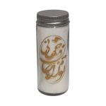 "White candle in a tall glass jar with a lit flame and prominent golden calligraphy design, on a dark brown table.")