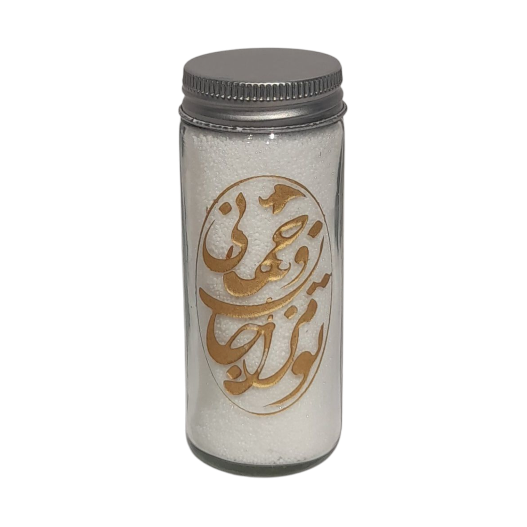 "White candle in a tall glass jar with a lit flame and prominent golden calligraphy design, on a dark brown table.")
